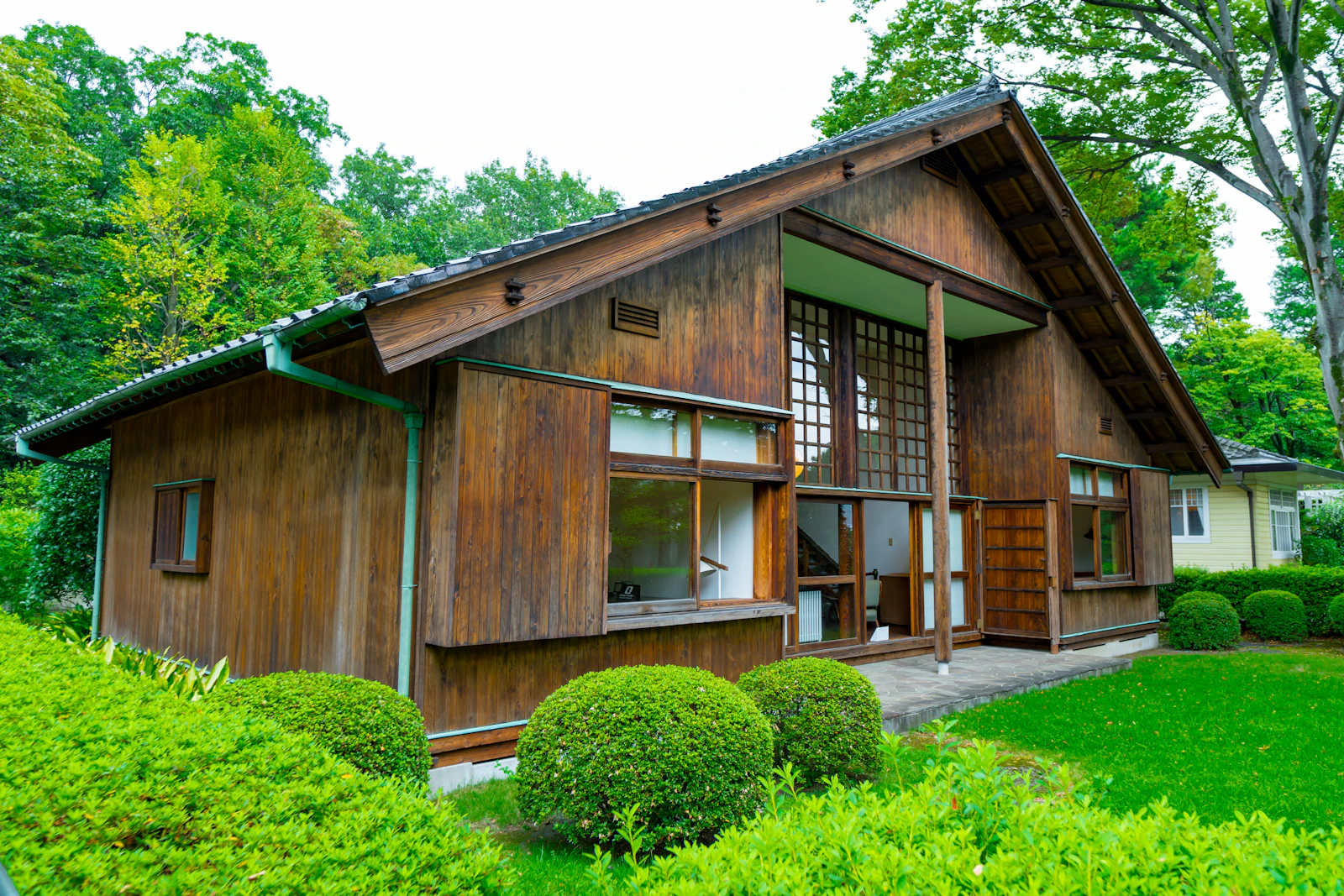 庭の緑に囲まれた、板張りの木の家