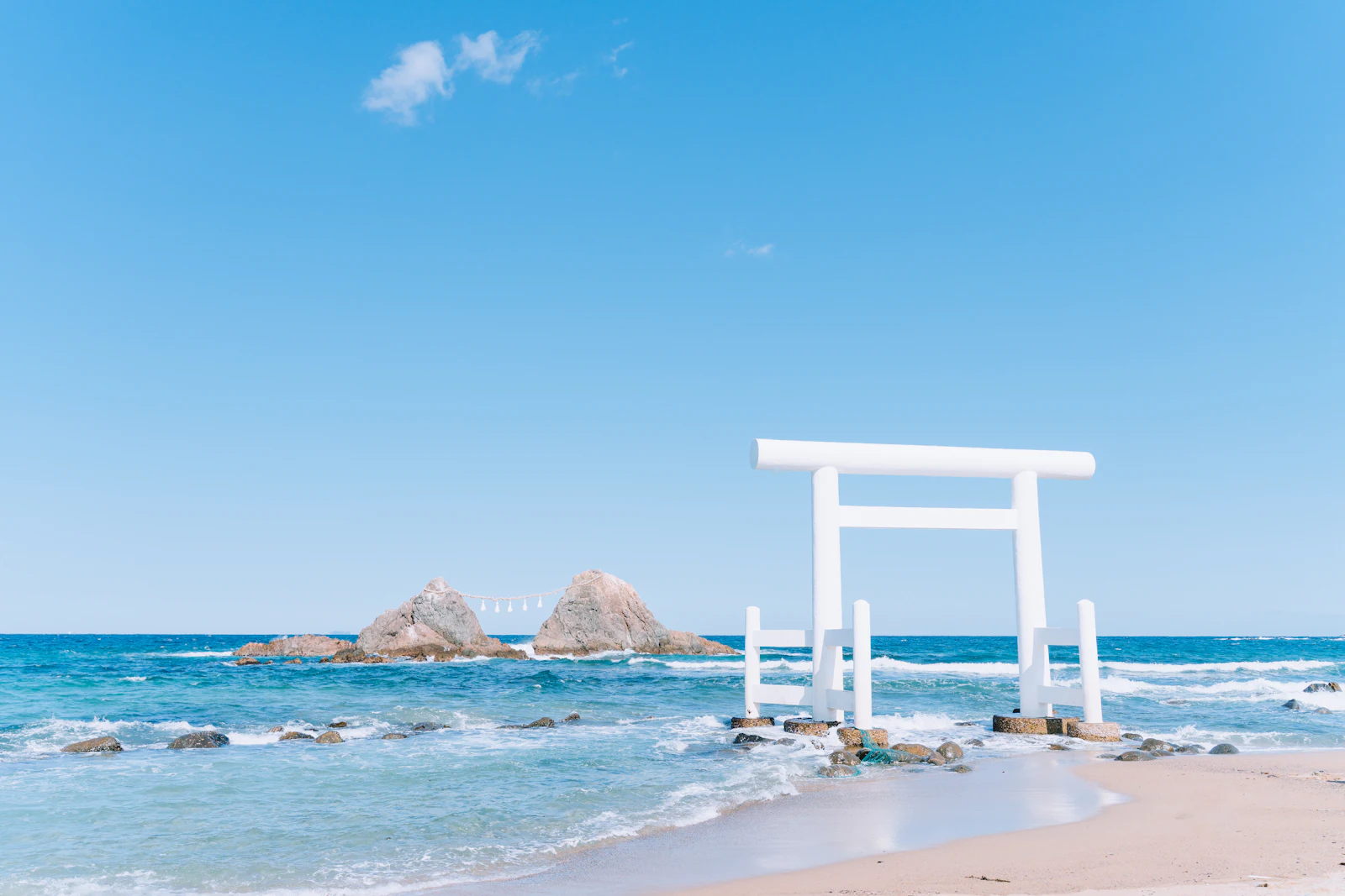 海の中に立つ白い鳥居と夫婦岩